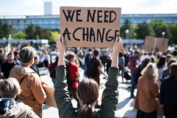 woman holding up a sign demanding change